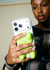 Person holding a phone with a green case in front of a mirror