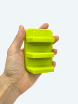 Hand holding a bright green silicone ice cube tray with 'Lekue' branding on a light gray background