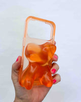 Hand holding a transparent orange phone case with a bear design on a white background