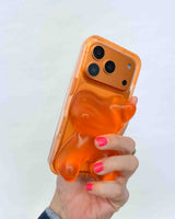 Hand holding a phone with an orange jelly bear case against a white background