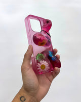 Hand holding a pink phone case with floral designs on a white background