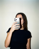 Person holding a phone with a glittery case against a plain background