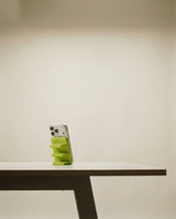 Phone with a green case on a white table against a beige wall