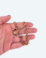 Gold chain and rings on a hand against a white background