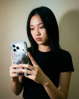 Woman holding a phone with a speckled case against a plain background